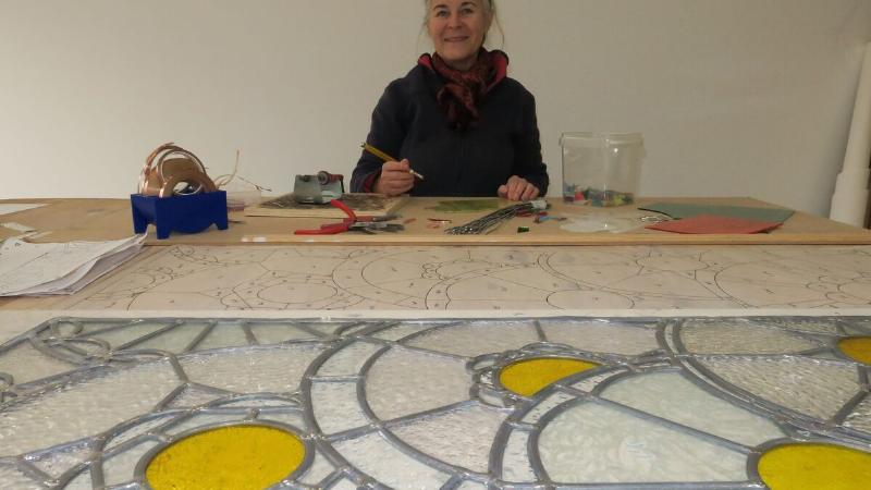Maître verrier assemblant des pièces de verre coloré pour le concours vitrail Notre Dame de Paris